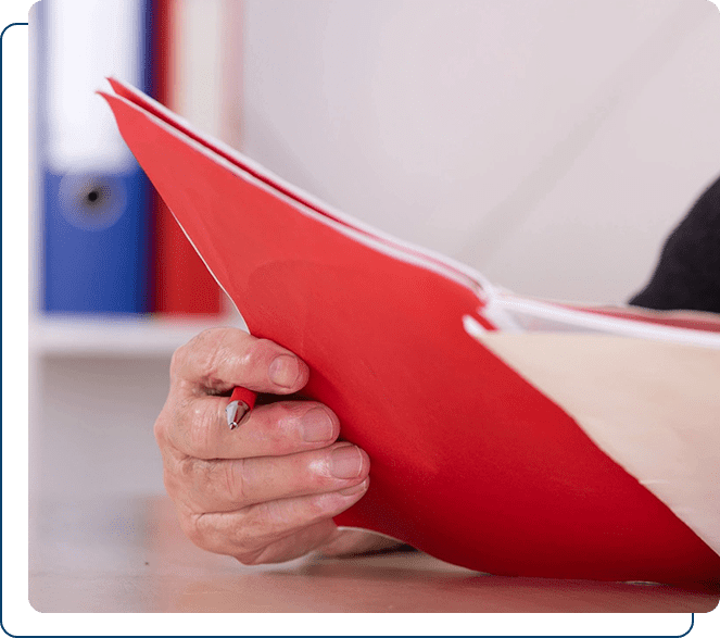 Close up of a hand holding a red folder with documents.