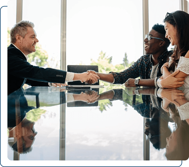 Two men and a woman smiling and shaking hands at a business meeting.