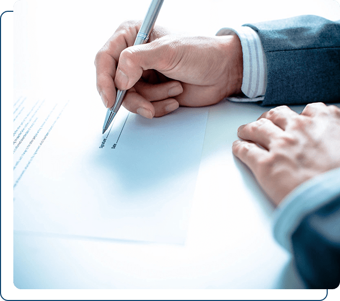 A person in a business suit signing a document on a desk.